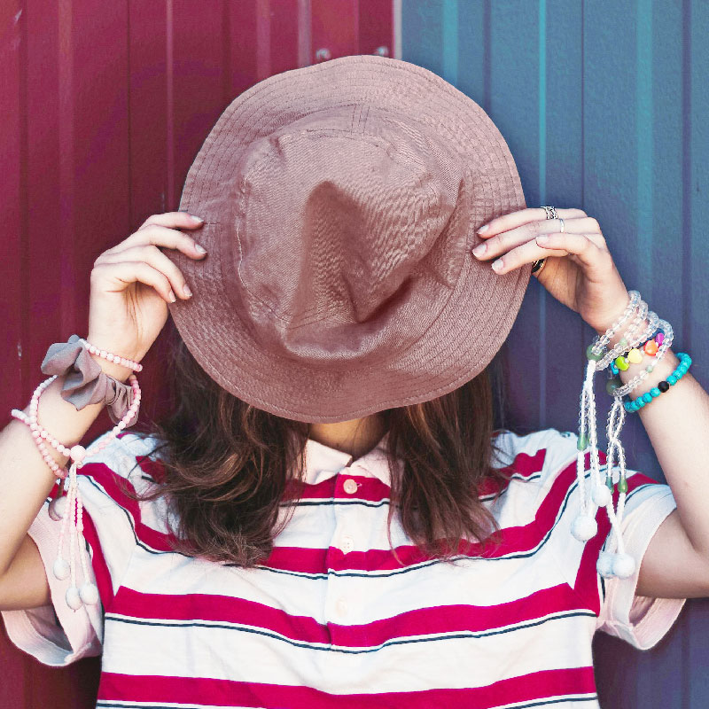 dziewczynka zasłania twarz letnim materiałowym kapeluszem
